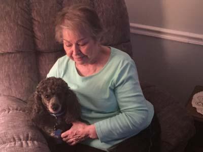 Barb holding her dog Tuxedo in a comfy recliner.
