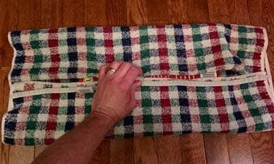 Making the book board Hand holding plaid fabric over books to make cat scratch board.