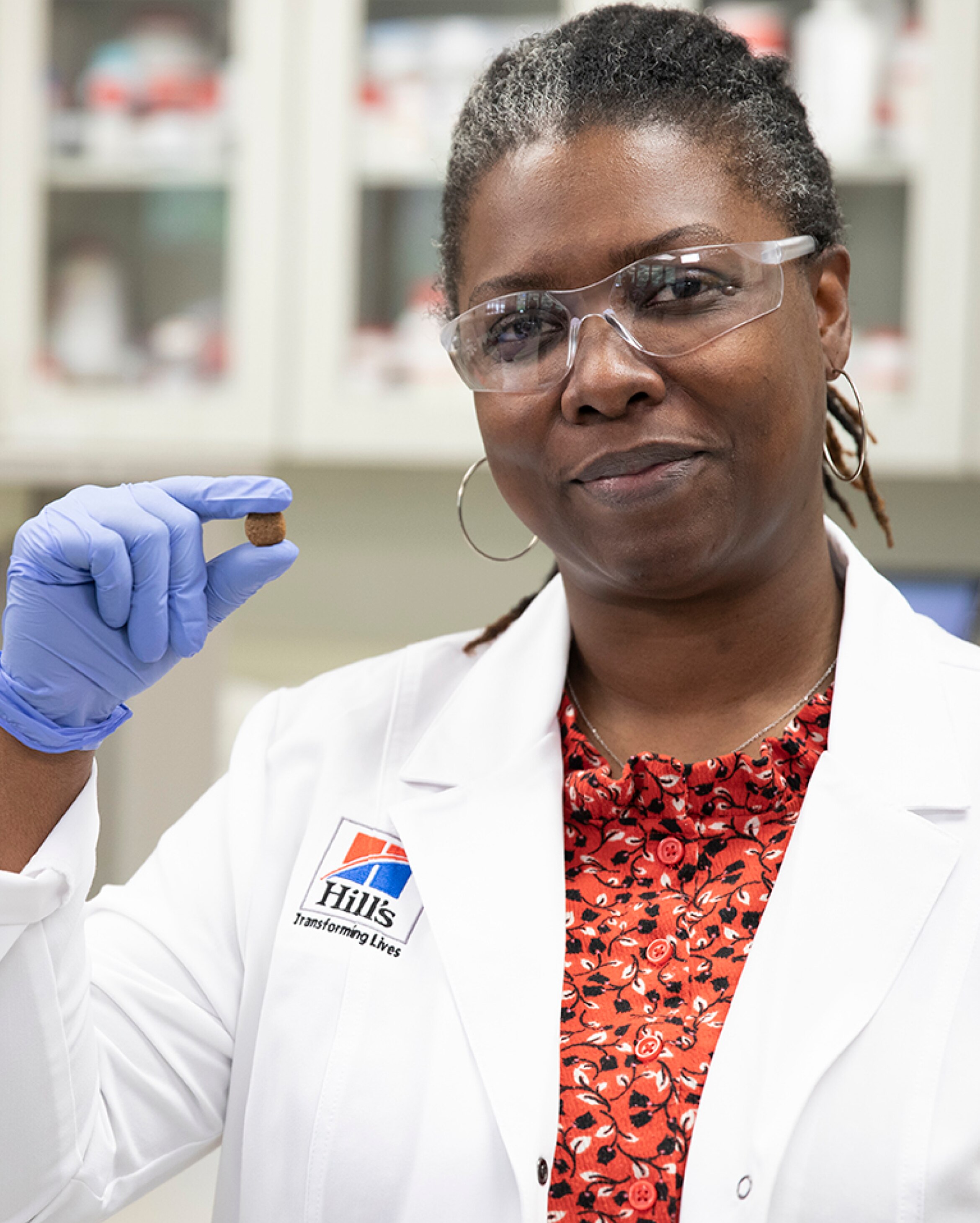 Uma cientista segurando o alimento para cães Hill's Pet na mão