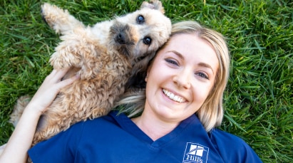 profissional de Hill's Pet deitado na grama com um cachorro
