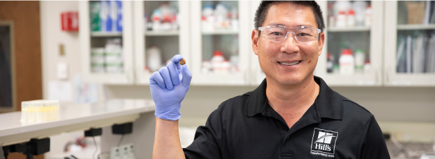 Pesquisador da Hill's Pet segurando ração para animais de estimação da Hill's Pet em sua mão